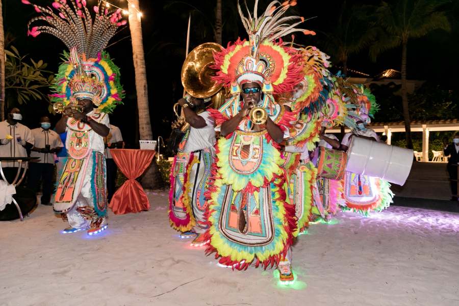 Lively musicians wearing colorful Caribbean dress perform with drums and trumpets