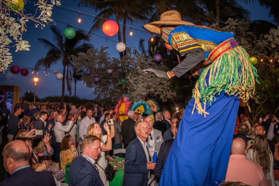 Event in Florida at evening with colorfully dressed entertainer on stilts wows nearby crowd