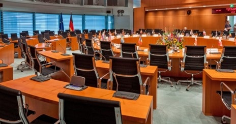 A modern conference room with rows of orange tables and black chairs